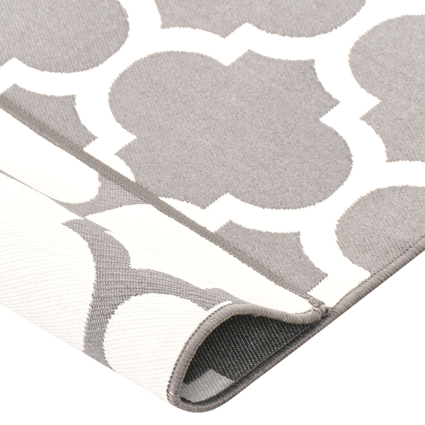 Moderner Balkon mit zwei Sesseln, hellem Beistelltisch, einer Pflanze im Topf und einem grau-weiß gemusterten Outdoor-Teppich.