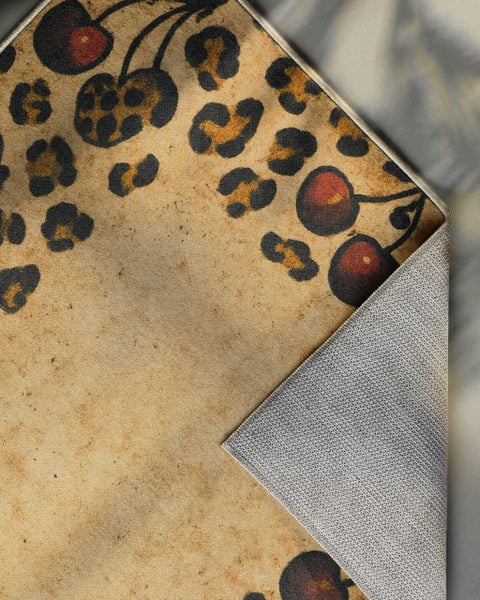 Teppich mit Leopardenmuster und Kirschen, eine Ecke ist umgeklappt und zeigt die rutschhemmende Rückseite.