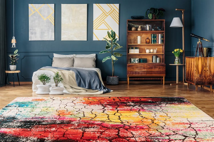 Nahaufnahme eines bunten Teppichs mit umgeklappter Ecke, grauer gewebter Rückseite und umkettelter Kante.