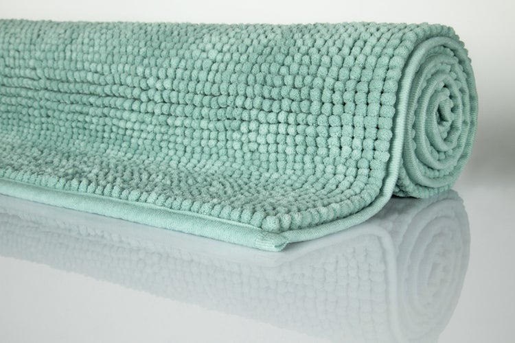 Zusammengerollte Badematte aus Chenille-Mikrofaser mit Noppen-Struktur in Türkis.