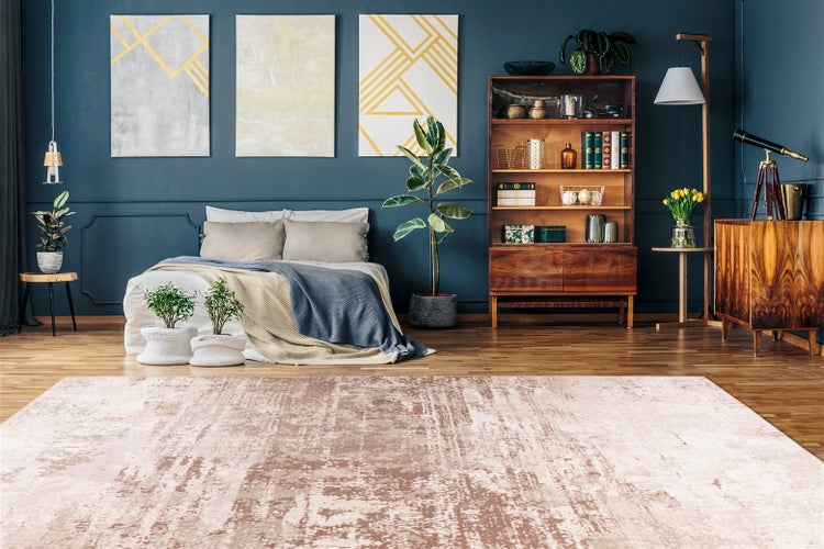 Modernes Schlafzimmer mit rosa Teppich in Vintage-Optik auf Holzfußboden, dunkle Wand, Holzmöbel, Zimmerpflanzen und organisierte Atmosphäre.