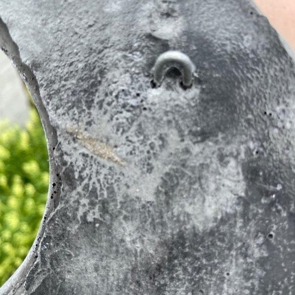 Detailansicht einer Betonoptik Oberfläche mit integriertem Metallaufhänger für Dekorationselemente