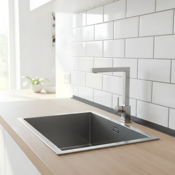 Moderne Küchenspüle aus Edelstahl mit Einhebelmischbatterie in einer hellen Küche mit Fliesenrückwand und Holzoptik Arbeitsplatte.
