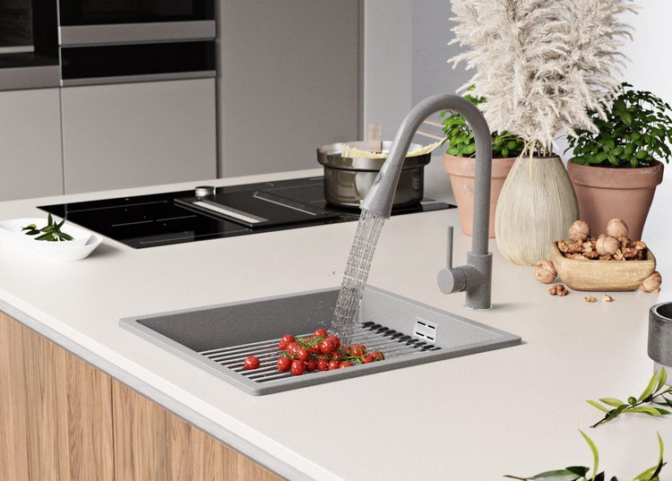 Küchenspüle mit Wasserhahn, Tomaten und Abtropfgitter in einer modernen Küche.
