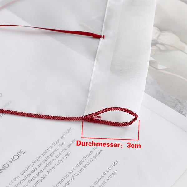 Detailaufnahme einer Gardine mit roter Zierschlaufe