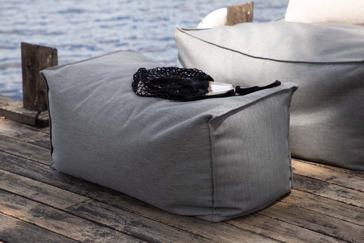 Wohnzimmer-Szene mit Holz-TV-Schrank, Pflanze, Büchern und Vase vor gemusterter Tapete