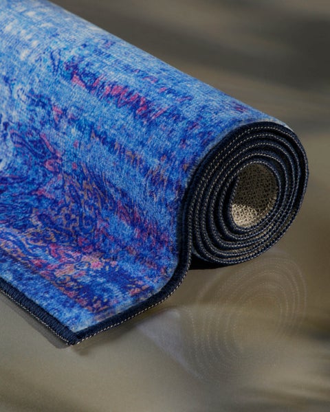 Gerollter blauer Teppich mit lila Muster und gekettelter Kante