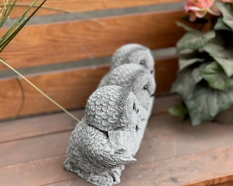 Gartenfigur Eulen-Trio aus Steinguss, drei kleine Eulen hintereinander aufgereiht auf Holz.