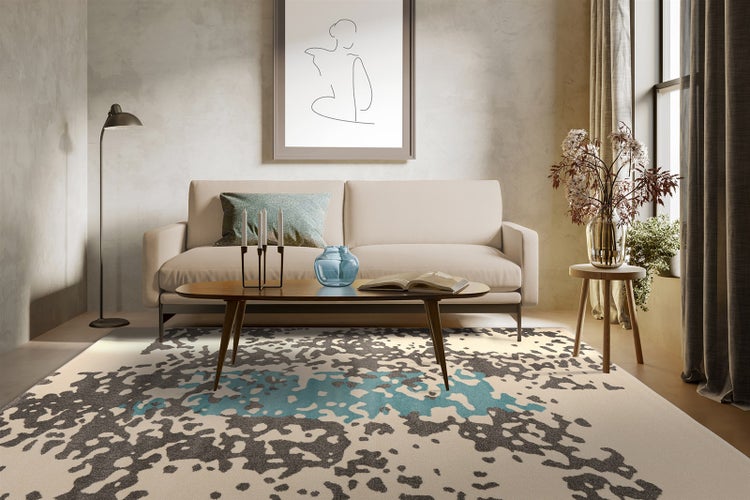 Helles Wohnzimmer mit abstraktem Teppich in Creme, Grau und Petrol. Mit cremefarbenem Sofa, Holztisch und minimalistischer Dekoration.