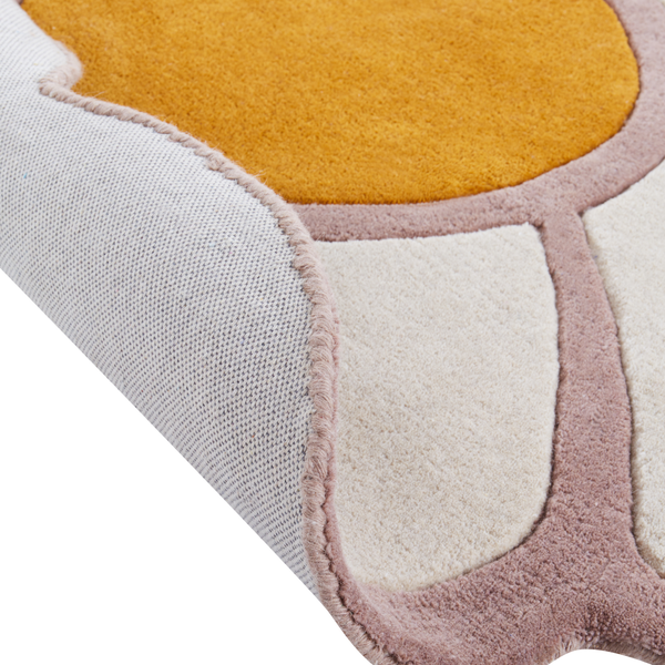 Weicher Teppich in Blumenform mit gelber Mitte, hellen Blütenblättern und rosa Umrandung.