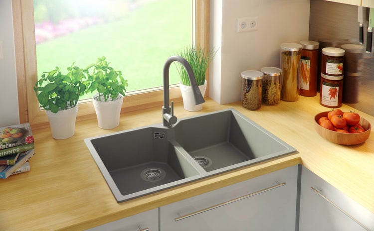 Küchenspüle mit zwei Becken, Wasserhahn und Arbeitsplatte in einer hellen Küche.