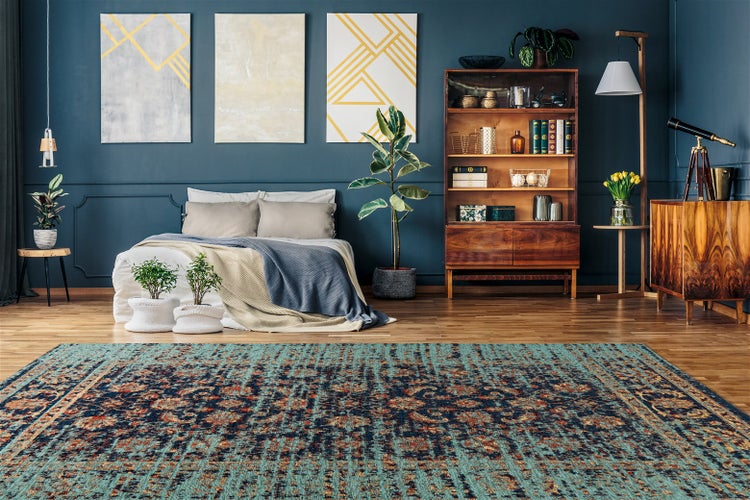 Großer gemusterter Teppich in einem Schlafzimmer mit Holzmöbeln, niedrigem Bett und Zimmerpflanzen auf Holzboden.