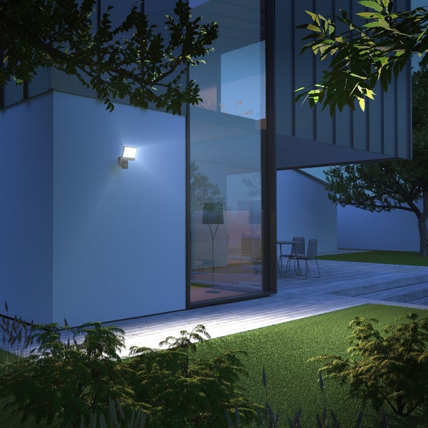 Moderne Außenwandleuchte mit LED Strahler zur Beleuchtung einer Hausfassade bei Nacht im Garten.