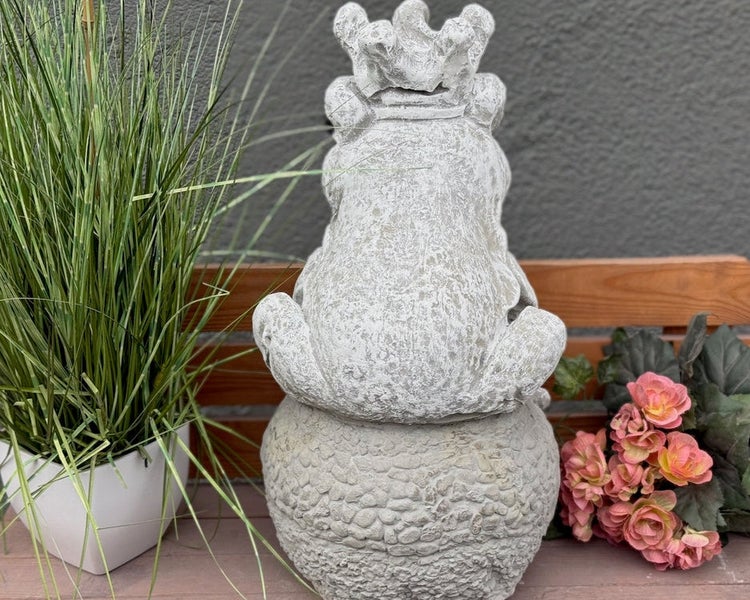 Gartenfigur Froschkönig aus Steinguss, sitzend auf einer strukturierten Kugel.