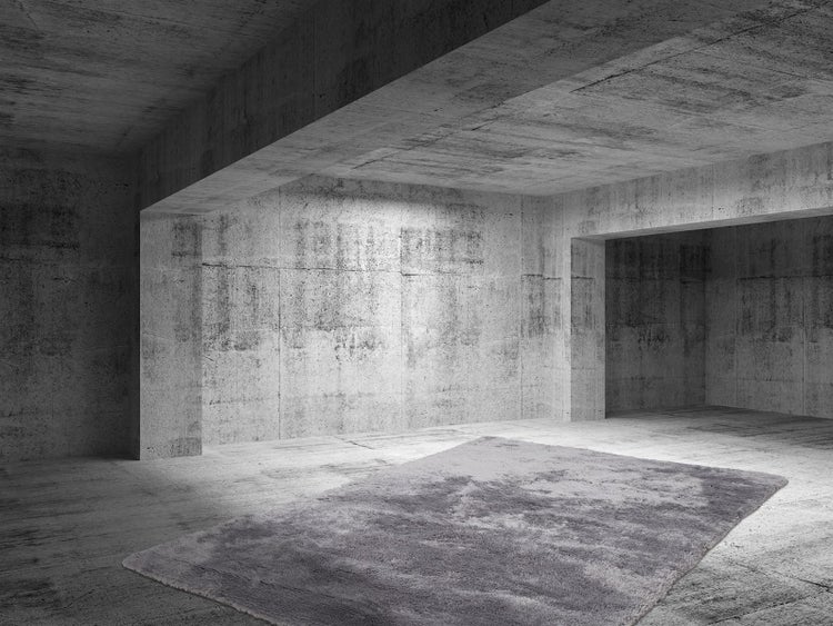 Grauer Hochflor-Teppich in einem minimalistischen Raum mit Wänden und Boden aus rohem Sichtbeton.