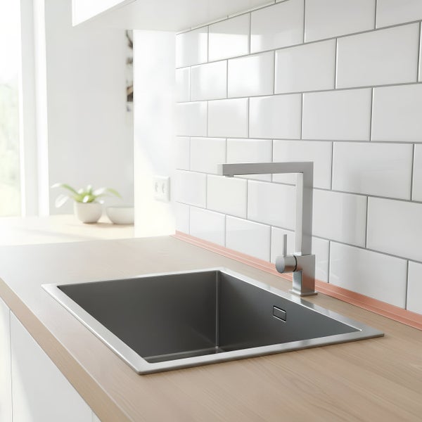 Moderne Küchenspüle aus Edelstahl mit quadratischem Einbaubecken und hoher Armatur vor einer Wand mit weißen Wandfliesen im Ziegelsteinmuster.
