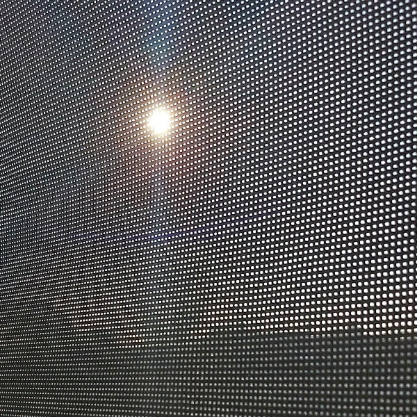 Nahaufnahme eines perforierten Bildschirms mit Sonneneinstrahlung