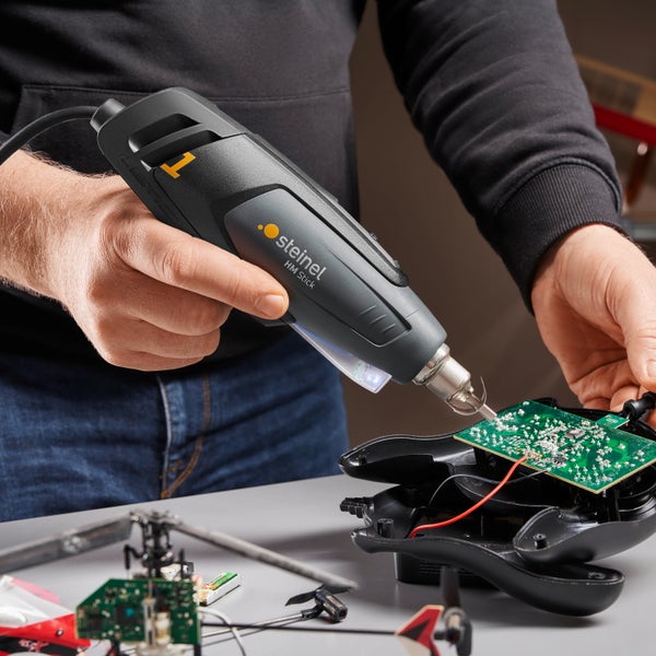 Eine Person benutzt eine Steinel Heißklebepistole HM Stick, um an einer elektronischen Platine zu arbeiten.