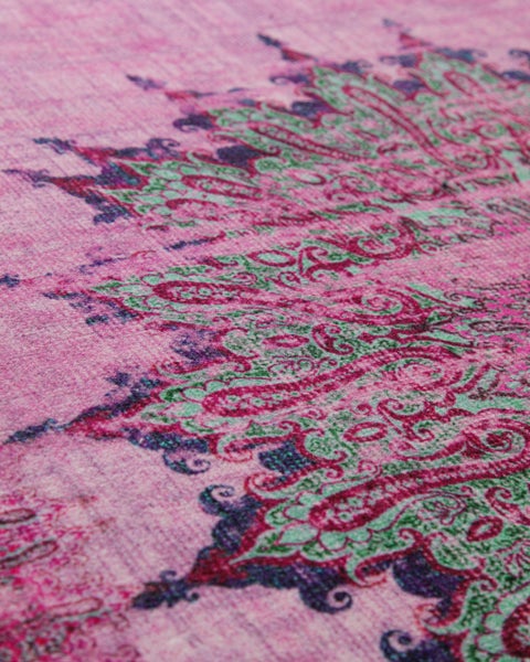 Nahaufnahme eines gewebten Teppichs in Rosa und Grün mit Paisley-Muster.