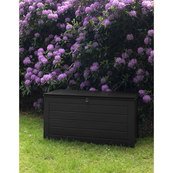 Anthrazitfarbene Gartenbox aus Kunststoff auf einer Rasenfläche vor einem blühenden Rhododendron.