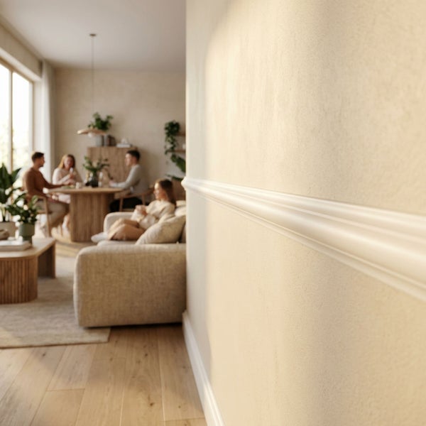 Wandleiste an einer strukturierten Wohnzimmerwand mit Blick auf einen hellen Wohnbereich mit Sitzgruppe und Essbereich im Hintergrund.