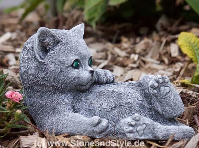 Dekorative Gartenfigur Katze aus Steinguss liegend im Gartenbeet