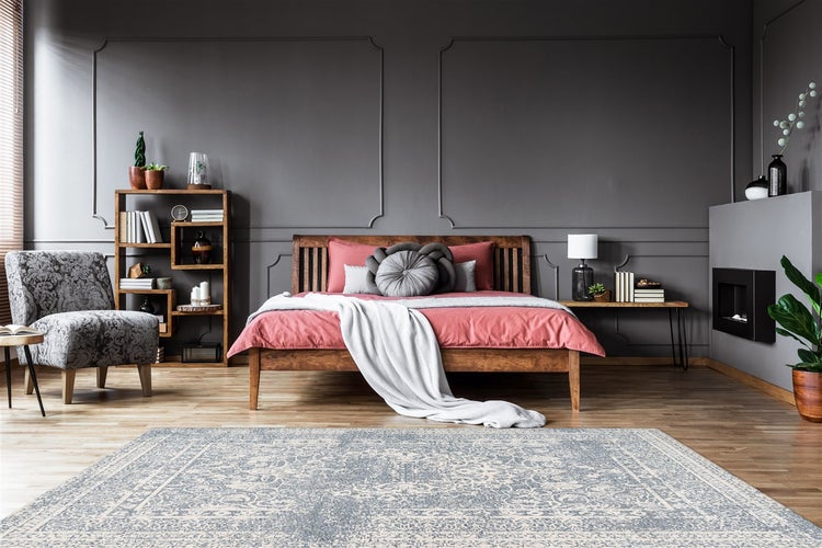 Modernes Schlafzimmer mit dunkelgrauen Wänden, Holzbett, Kamin, gemustertem Sessel und großem Teppich auf Holzfußboden.