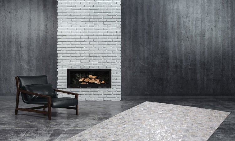 Modernes Wohnzimmer mit weißem Backsteinkamin, schwarzem Ledersessel und geometrisch gemustertem Teppich auf Betonboden im Industriedesign.