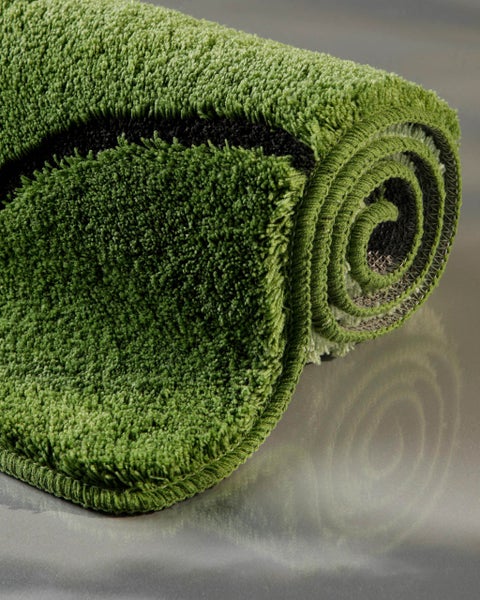 Grüner hochfloriger Badteppich mit schwarzem Muster, weiches Material, zusammengerollt.