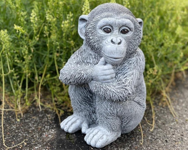 Detaillierte Steinfigur eines sitzenden Schimpansen für den Garten, naturgetreue Gartendekoration als Tierfigur aus witterungsbeständigem Material.