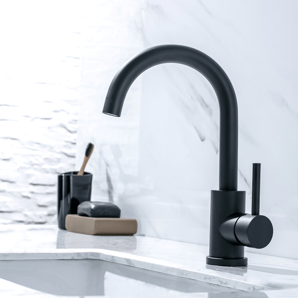 Moderne Waschtischarmatur in geschwungenem Design auf einer Marmoroberfläche mit Badezimmerzubehör.