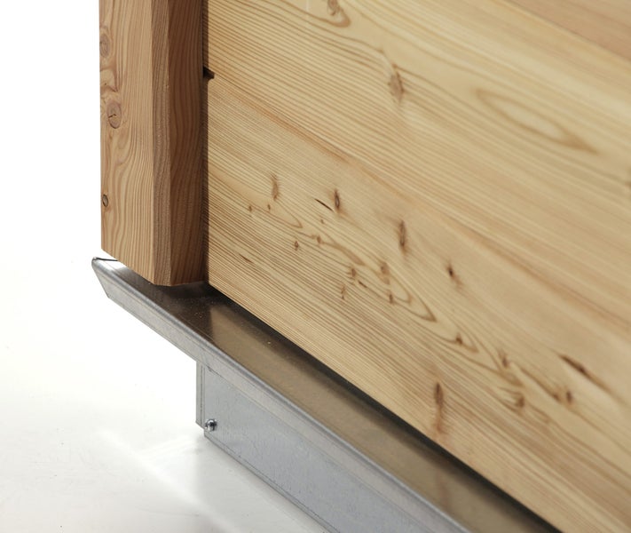 Detailansicht eines Hochbeets aus Holz mit einem schützenden Metallprofil am Boden.