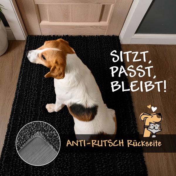 Dunkelgraue Badematte mit Noppenstruktur und rutschfester Rückseite, ein Hund sitzt auf dem Teppich vor einer Holztür.