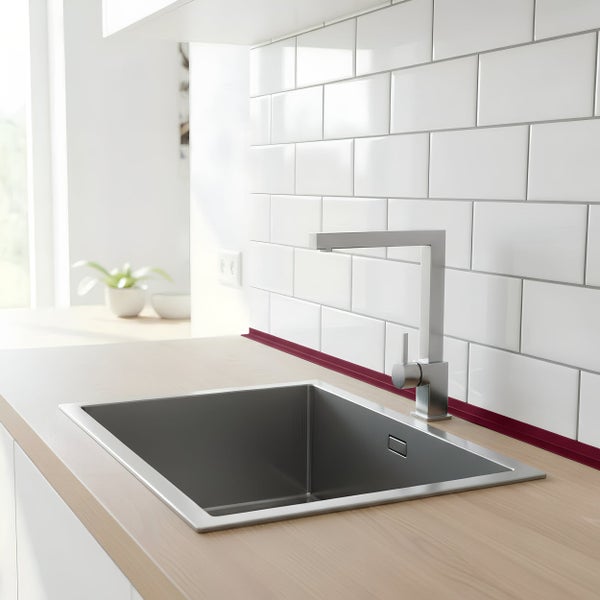 Moderne Küchenspüle aus Edelstahl mit quadratischer Armatur eingelassen in eine helle Holzarbeitsplatte vor einer weißen Fliesenrückwand.