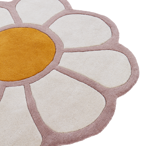 Hell eingerichtetes Kinderzimmer mit einem Teppich in Blumenform, einem Hausbett aus Holz, hellem Holzboden und einem Wandregal mit Dekoration.