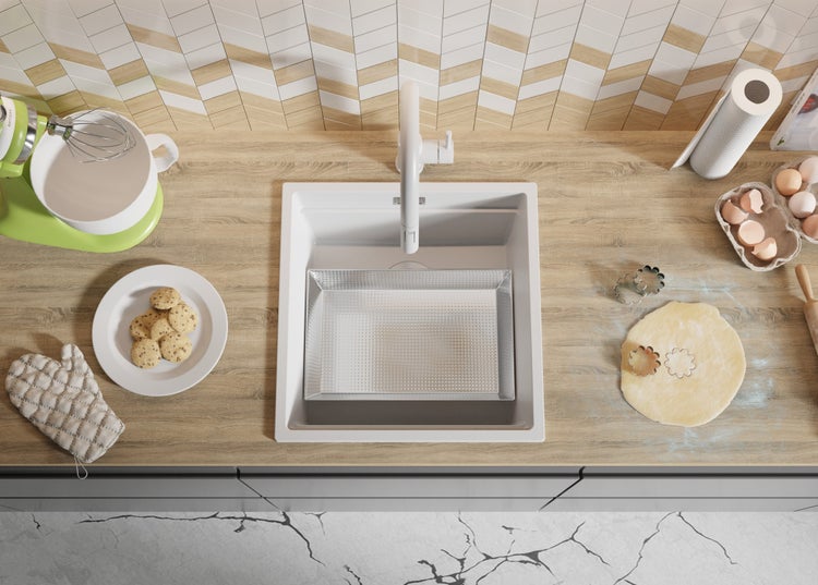 Küchenszene mit Spüle, Armatur, Teig, Plätzchenausstecher und weiteren Küchenutensilien auf einer Arbeitsplatte.