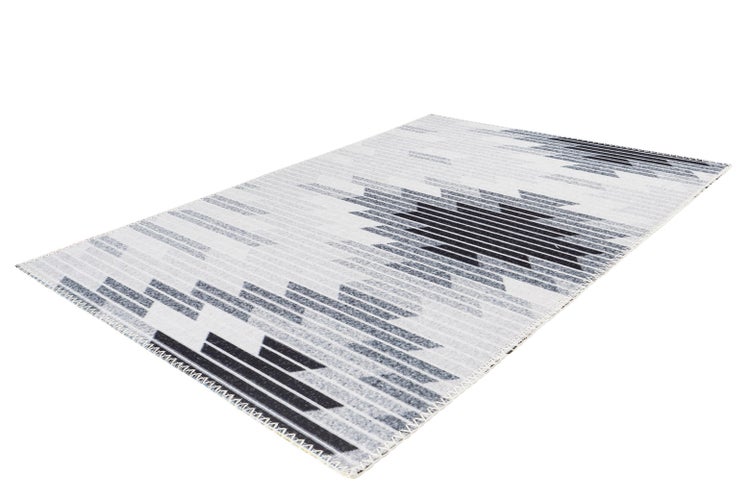 Rechteckiger grau-weißer Teppich mit geometrischem Ethno-Muster aus Streifen und Rauten in Schrägansicht.
