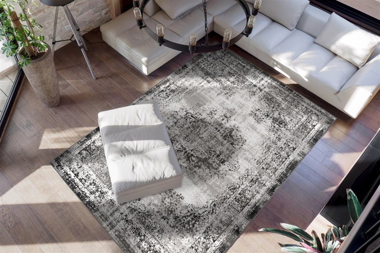 Moderner, heller Wohnraum mit weißem Ledersofa und rechteckigem Teppich im grauschwarzen Vintage-Design auf dunklem Holzboden.