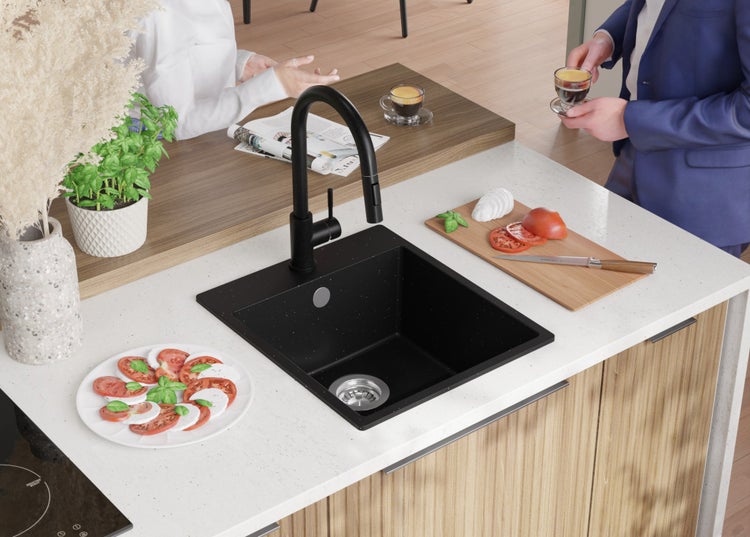 Schwarze Küchenspüle mit Wasserhahn auf einer Küchentheke mit Speisen