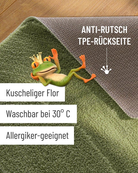 Grüne rechteckige Badematte mit Muster in hellem Badezimmer auf Holzboden neben freistehender Badewanne und Rattan-Beistelltisch.