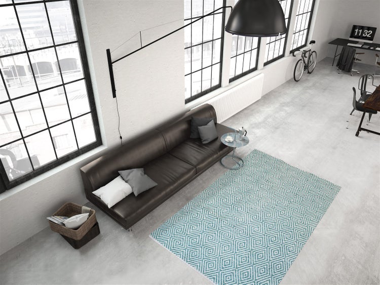 Modernes Wohnzimmer im Industriestil mit Ledersofa, geometrisch gemustertem Teppich, Betonboden und großen Sprossenfenstern.