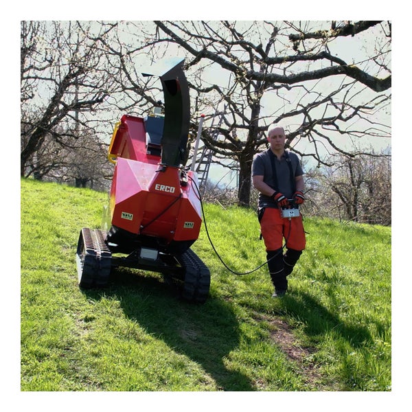 Raupenhäcksler mit Bedienperson auf einer grünen Wiese