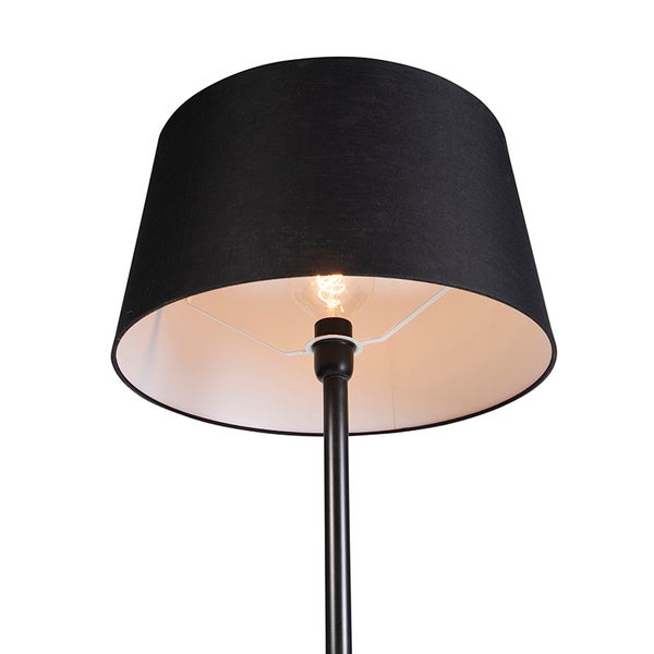 Stehlampe mit schwarzem Lampenschirm und eingeschalteter Glühbirne.