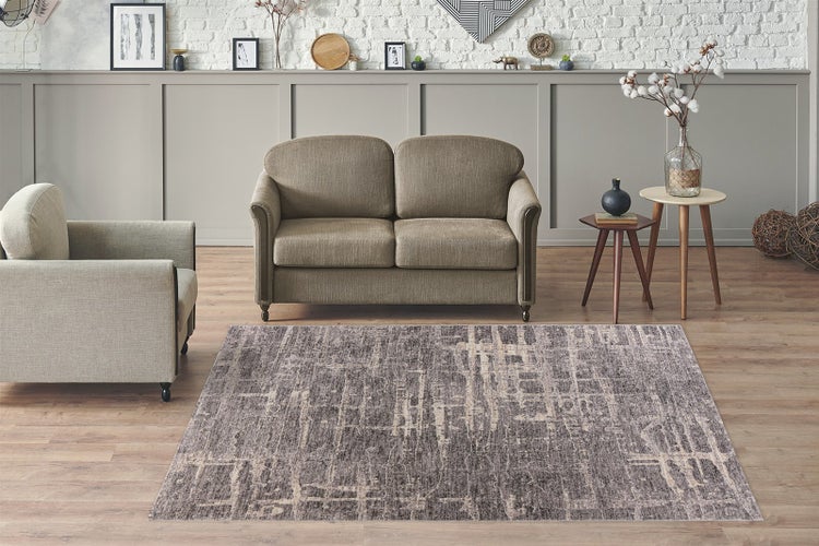 Moderner, hell gestalteter Wohnbereich mit gemustertem Teppich auf Holzboden, einem Zweisitzer-Sofa und einem Sessel.