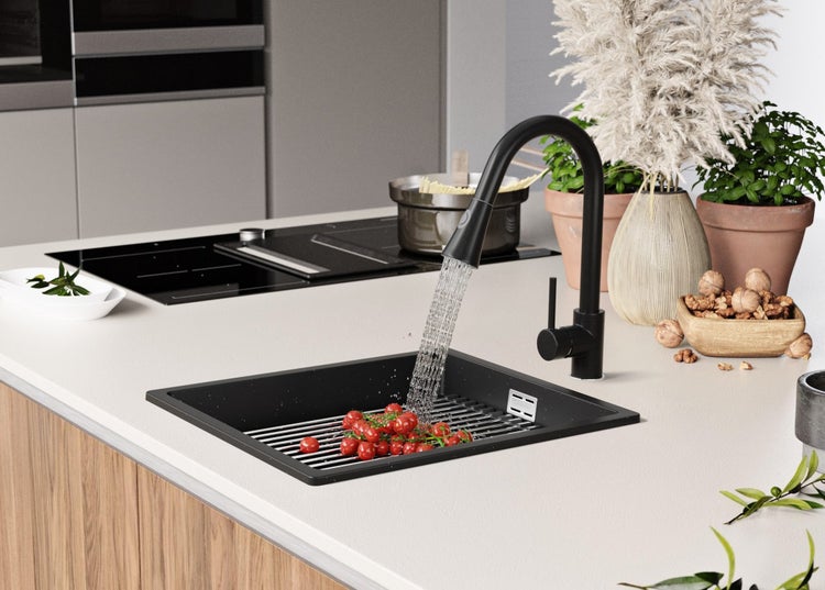 Schwarze Küchenspüle mit Abtropfgitter und Wasserhahn in moderner Küchenumgebung.