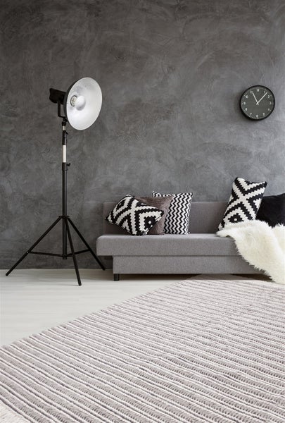 Detailaufnahme eines geflochtenen Teppichs aus Wolle mit horizontalem Muster und langen Fransen.