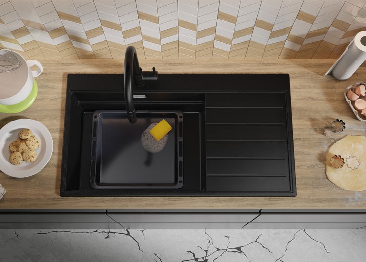 Draufsicht auf eine Küche mit Spüle, Backblech, Lebensmitteln und Küchenutensilien auf einer Arbeitsfläche.