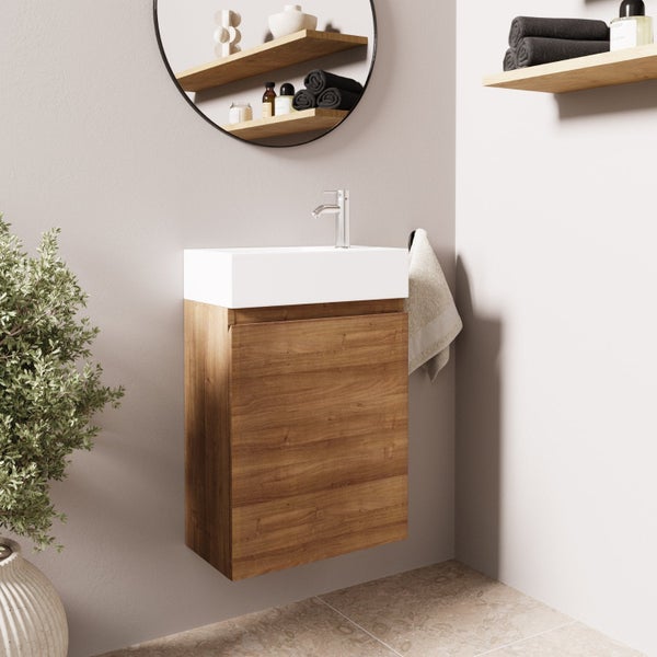 Ein wandhängender Waschtischunterschrank in Holzoptik mit einem weißen Keramikwaschbecken und einer modernen Armatur in einem Badezimmer.