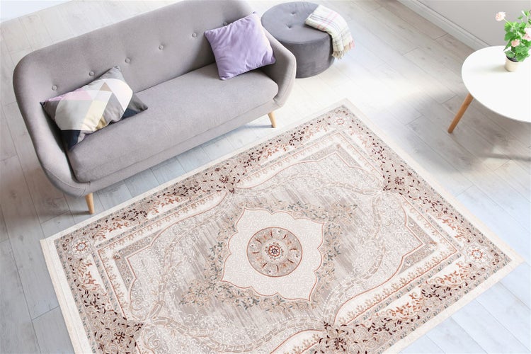 Heller, organisierter Wohnraum mit rechteckigem Orient-Teppich vor einem grauen Sofa auf hellem Holzboden.