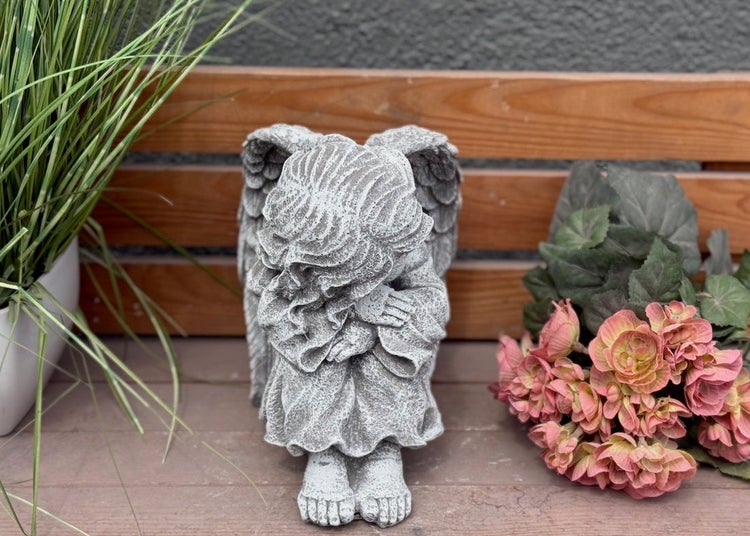Sitzende Engelsfigur aus Stein mit Flügeln als Grabschmuck oder Gartendekoration.